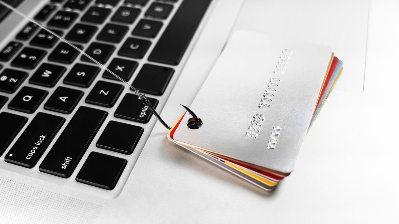 A fishing hook catching credit cards next to a computer